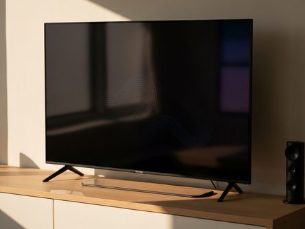 소파에 앉아 TV를 시청하는 사람들의 뒷모습과 리모컨, 팝콘이 놓인 거실 풍경