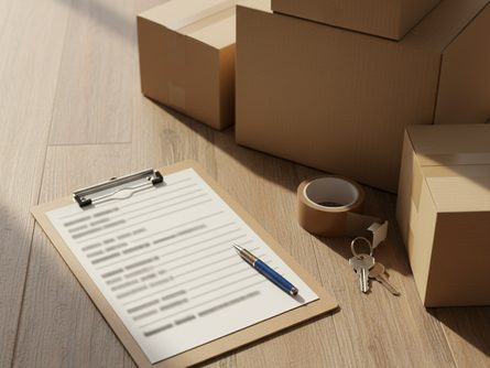 체크리스트가 적힌 클립보드, 볼펜, 이사 박스, 테이프, 열쇠가 놓인 나무 바닥